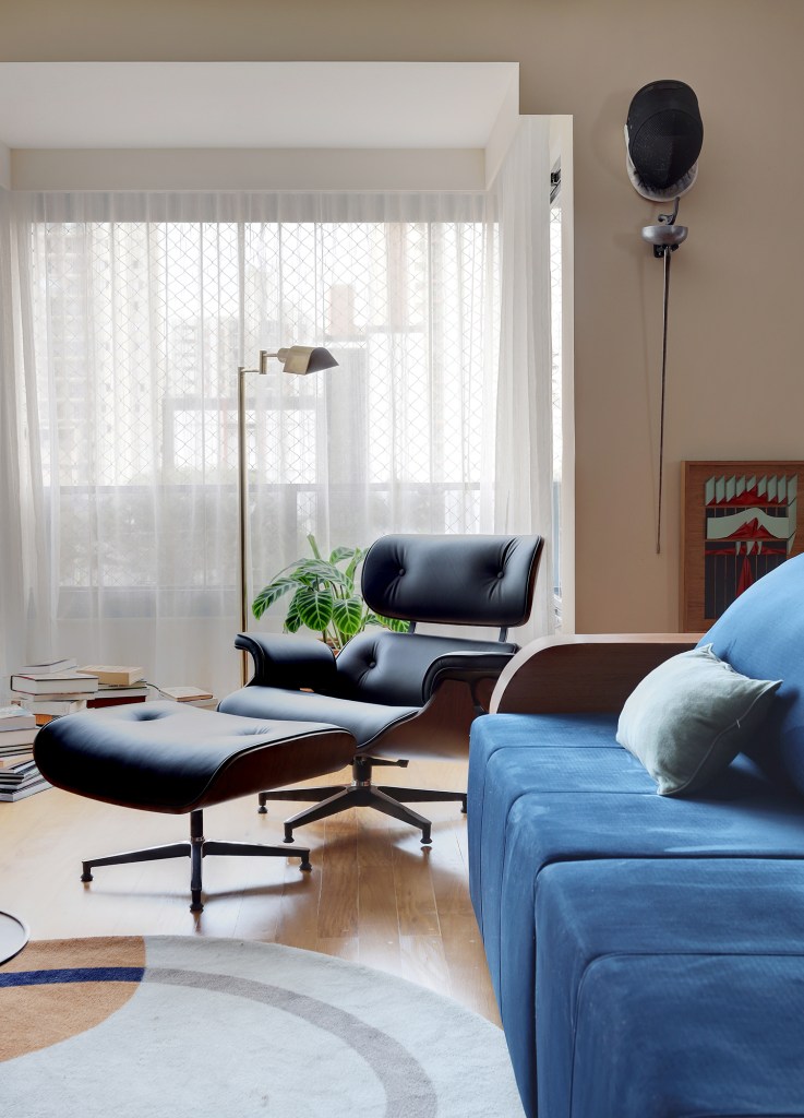 Peças retrôs e décor futurista se encontram no apartamento de 90 m². Projeto Trees Arquitetura. Na foto, sala de estar com sofá azul e canto de leitura.