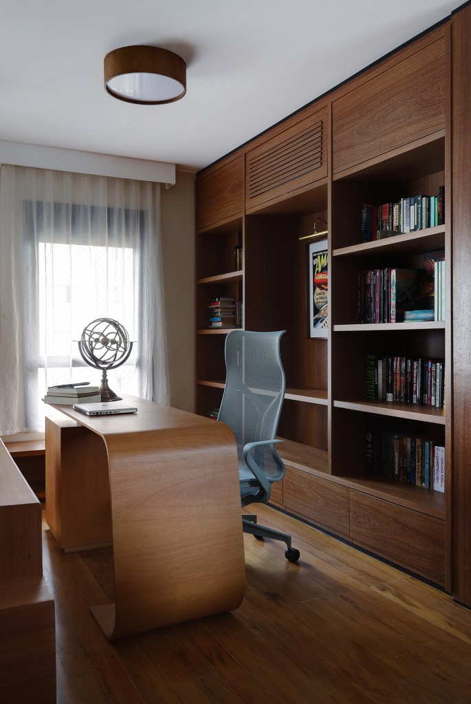 Peças retrôs e décor futurista se encontram no apartamento de 90 m². Projeto Trees Arquitetura. Na foto, home office com móveis de madeira.
