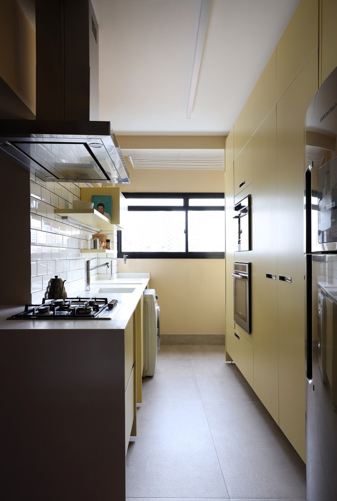 Peças retrôs e décor futurista se encontram no apartamento de 90 m². Projeto Trees Arquitetura. Na foto, cozinha com marcenaria amarela e subway tiles.