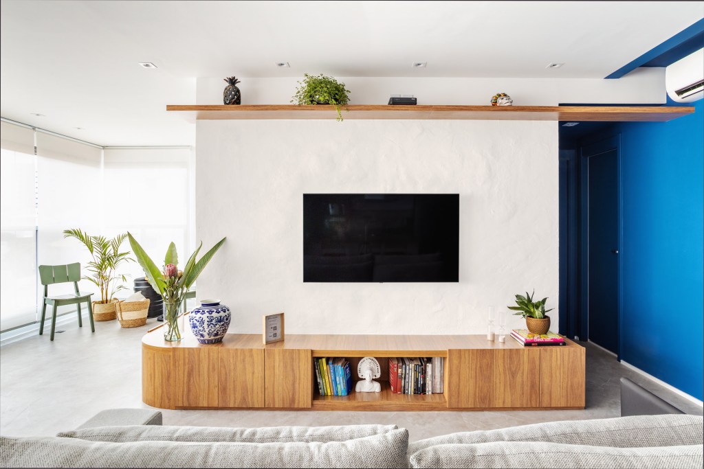 Sala de tv com rack curvo e paredes off white.