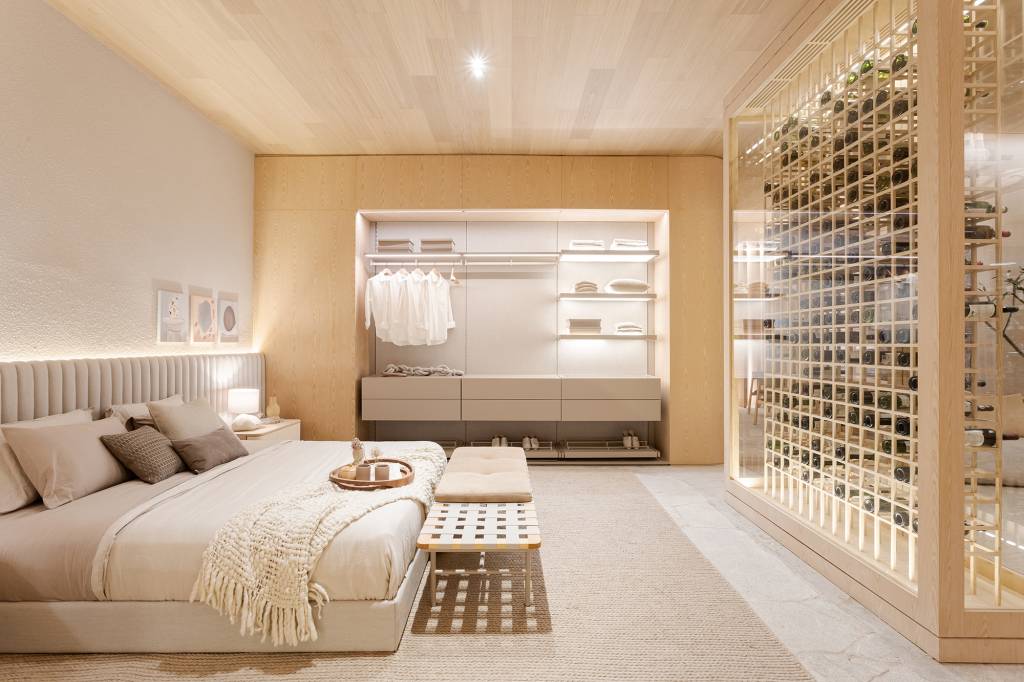 Adega para 300 garrafas separa living de quarto neste loft de 150 m². Projeto de Figueiredo Fischer Arquitetos para a CASACOR SP 2023. Na foto, quarto com closet aberto, adega e cabeceira estofada.