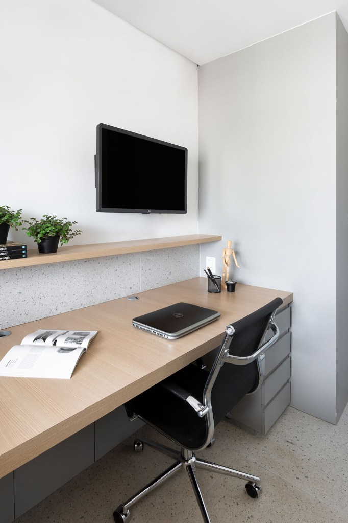 Apê de 142 m² ganha décor neutro que se integra aos eletrodomésticos. Projeto Degradê Arquitetura. Na foto, home office com TV e prateleira.