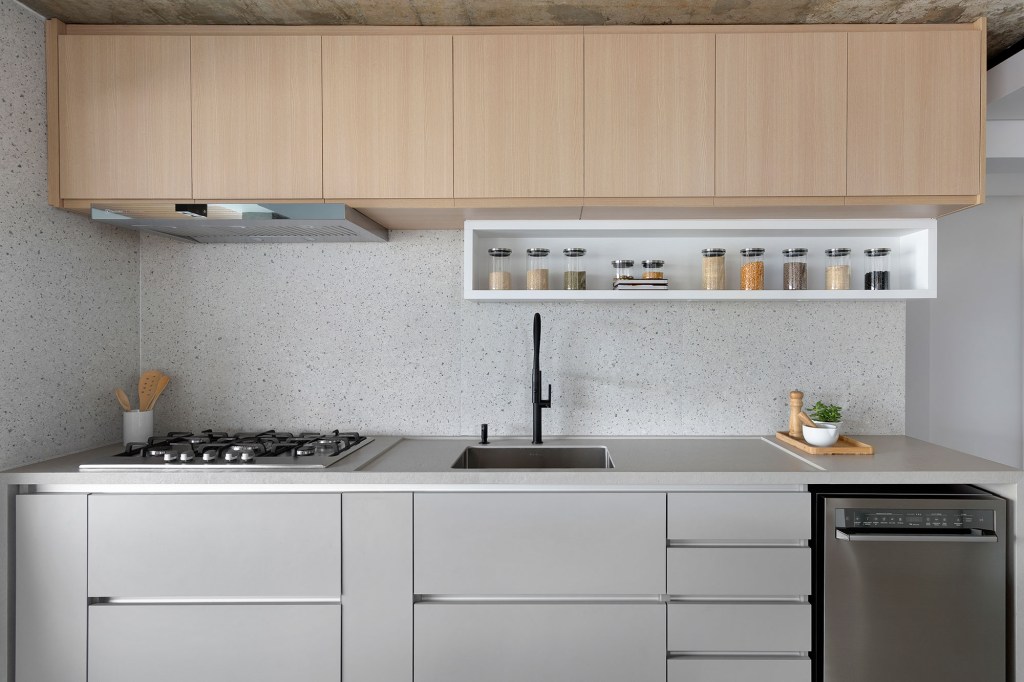 Apê de 142 m² ganha décor neutro que se integra aos eletrodomésticos. Projeto Degradê Arquitetura. Na foto, cozinha com parede com textura de granilite.