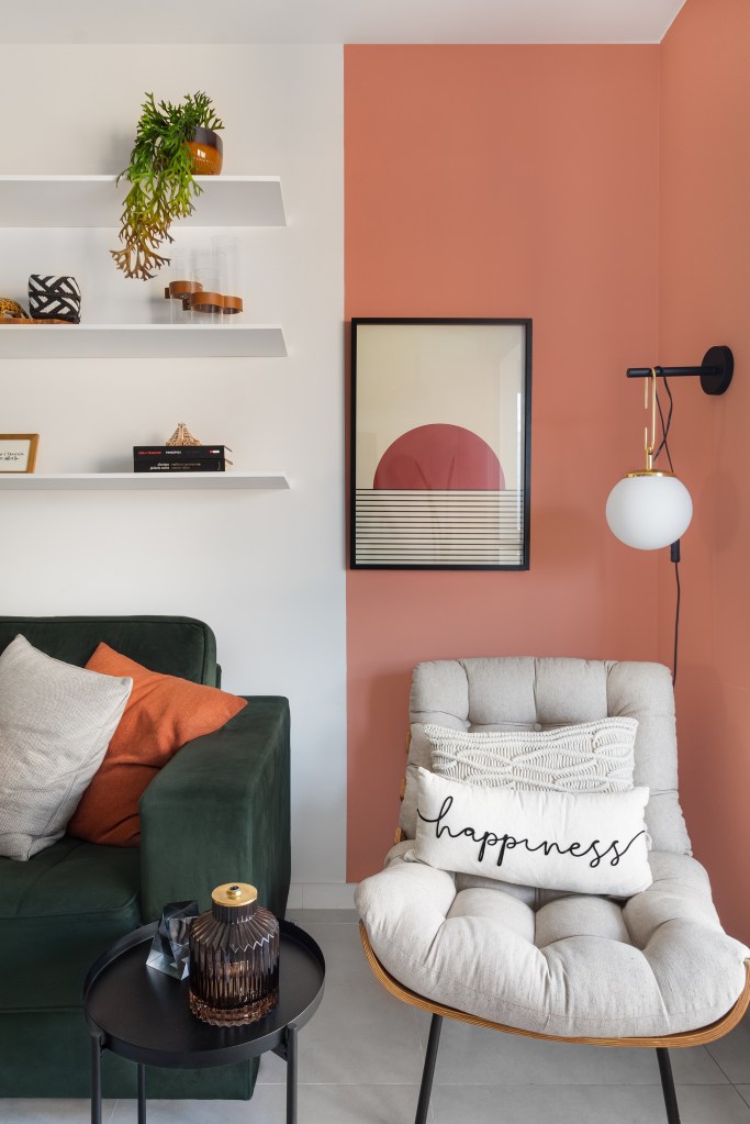 Apartamento colorido de 65 m² é cheio de referências ao pop art. Projeto de Pistache Arquitetura. Na foto, canto de leitura com poltrona, parede rosa e sofá verde.