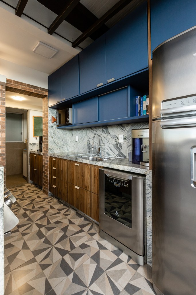 Cozinha integrada com marcenaria azul e piso de ladrilho geométrico.