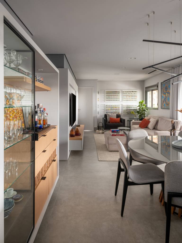 ape-155m-paleta-de-cores-sobria-cozinha-forma-u-sotaque-arquitetura-06 Sala de tv integrada com jantar e cozinha com piso de porcelanato cinza e mesa redonda.