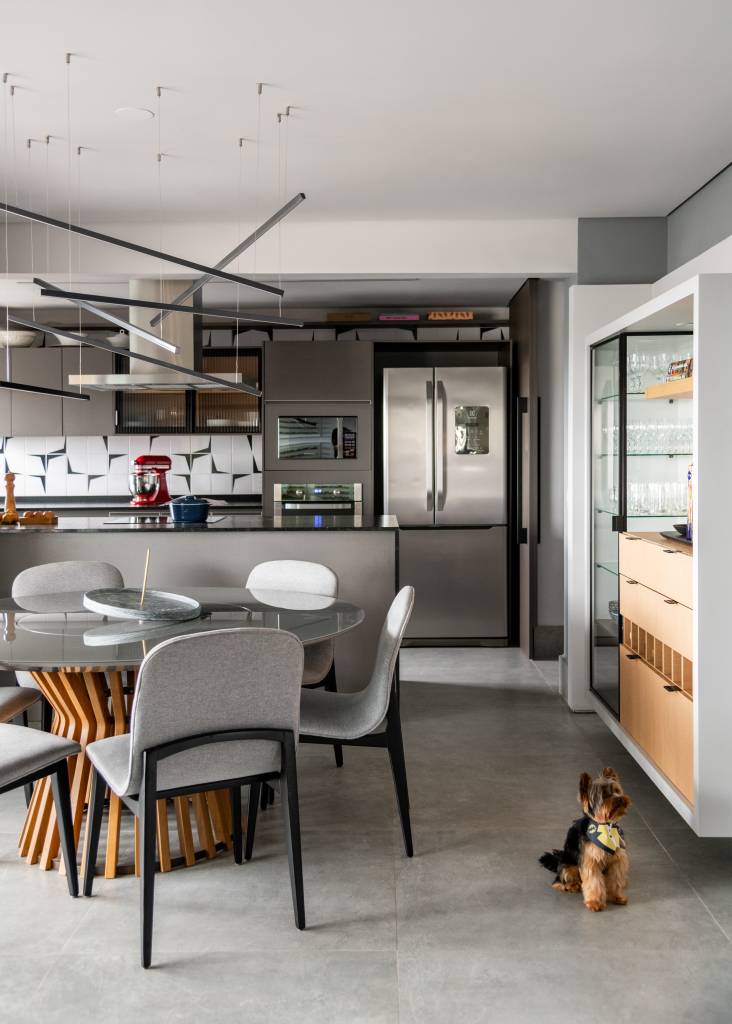 ape-155m-paleta-de-cores-sobria-cozinha-forma-u-sotaque-arquitetura-14 Sala de tv integrada com jantar e cozinha com piso de porcelanato cinza e mesa redonda.