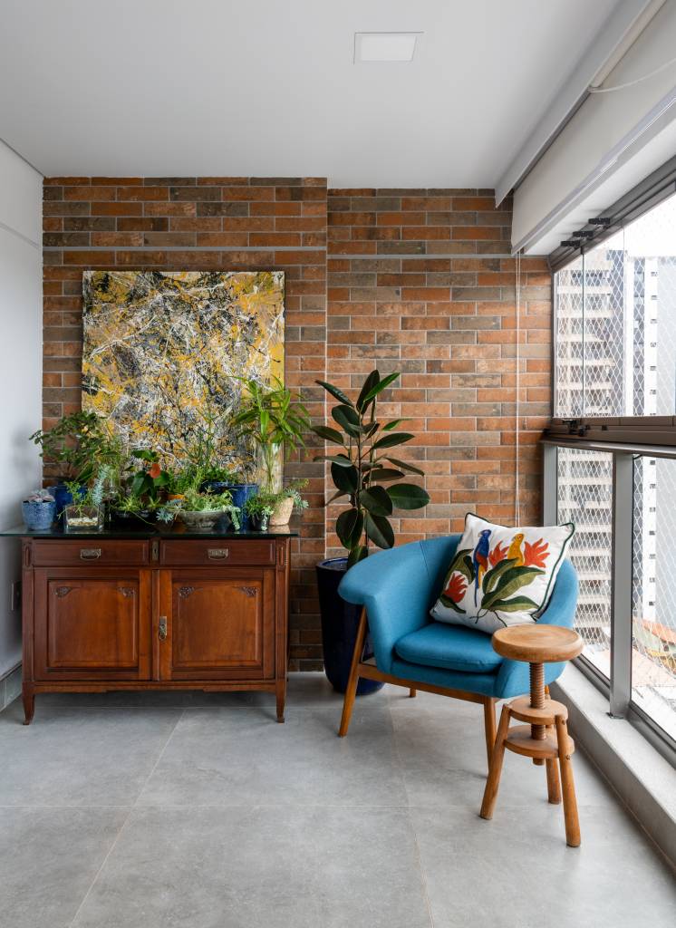 ape-155m-paleta-de-cores-sobria-cozinha-forma-u-sotaque-arquitetura-18-varanda Varanda integrada com parede de tijolinhos e poltrona azul