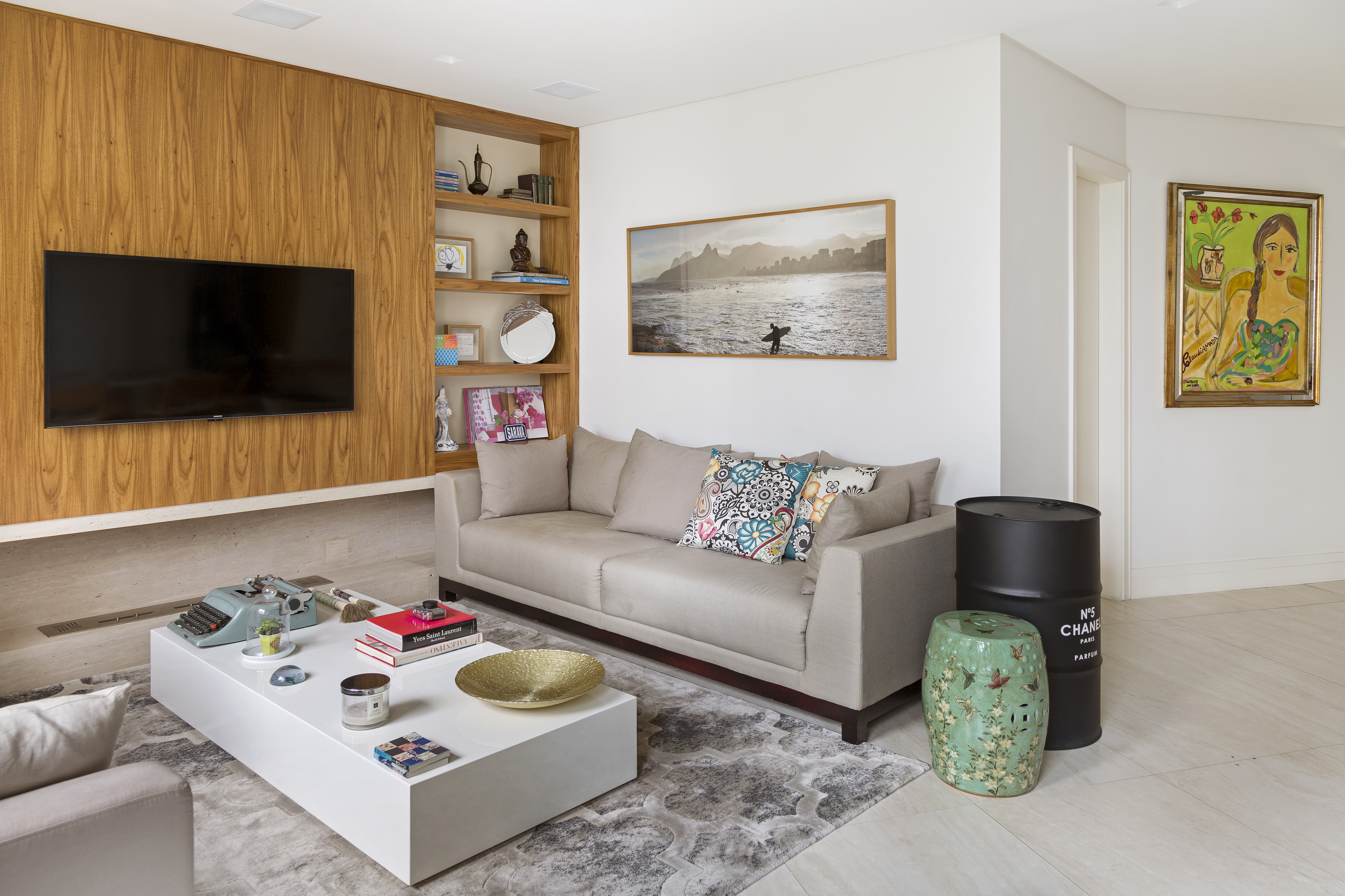 Sala de estar pequena com sofá cinza, tapete cinza, mesa de centro branca e parede revestida de madeira.