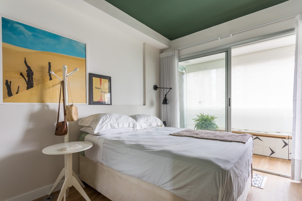 Quarto com teto verde, cama de casal, cabideiro branco e armário baixo.