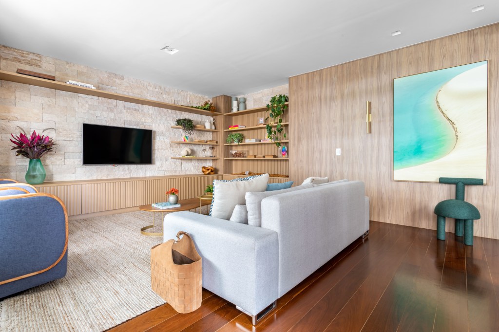 Sala de estar com piso de madeira, parede revestida de madeira e sofá branco.