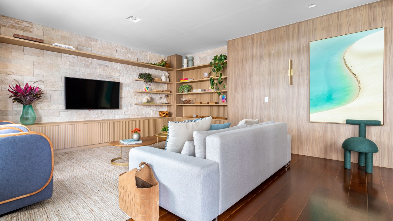 Sala de estar com piso de madeira, parede revestida de madeira e sofá branco.