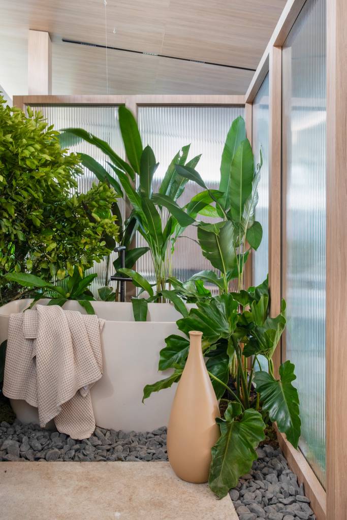 Casa de 110 m² mescla o contemporâneo com a tradição de Minas Gerais. Projeto Navarro Arquitetura para a CASACOR SP 2023. NA foto, banheiro com banheira, plantas e pedras.