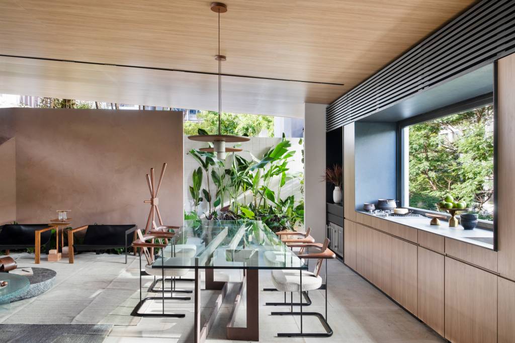 Casa de 110 m² mescla o contemporâneo com a tradição de Minas Gerais. Projeto Navarro Arquitetura para a CASACOR SP 2023. Na foto. cozinha e sala de jantar com plantas, tapete e marcenaria.