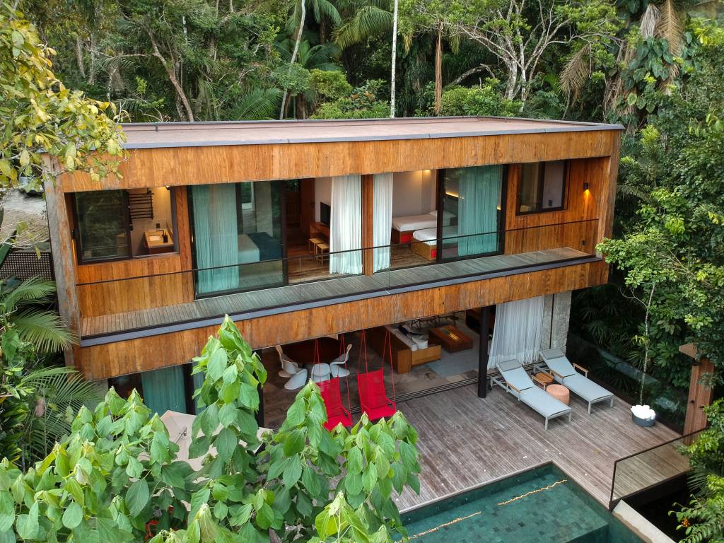 Casa de 153 m² se camufla em meio à natureza do litoral paulista. Projeto de Daniel Fromer, interiores de Julyana Bortolotto. Na foto, fachada com varandas dos quartos e piscina.