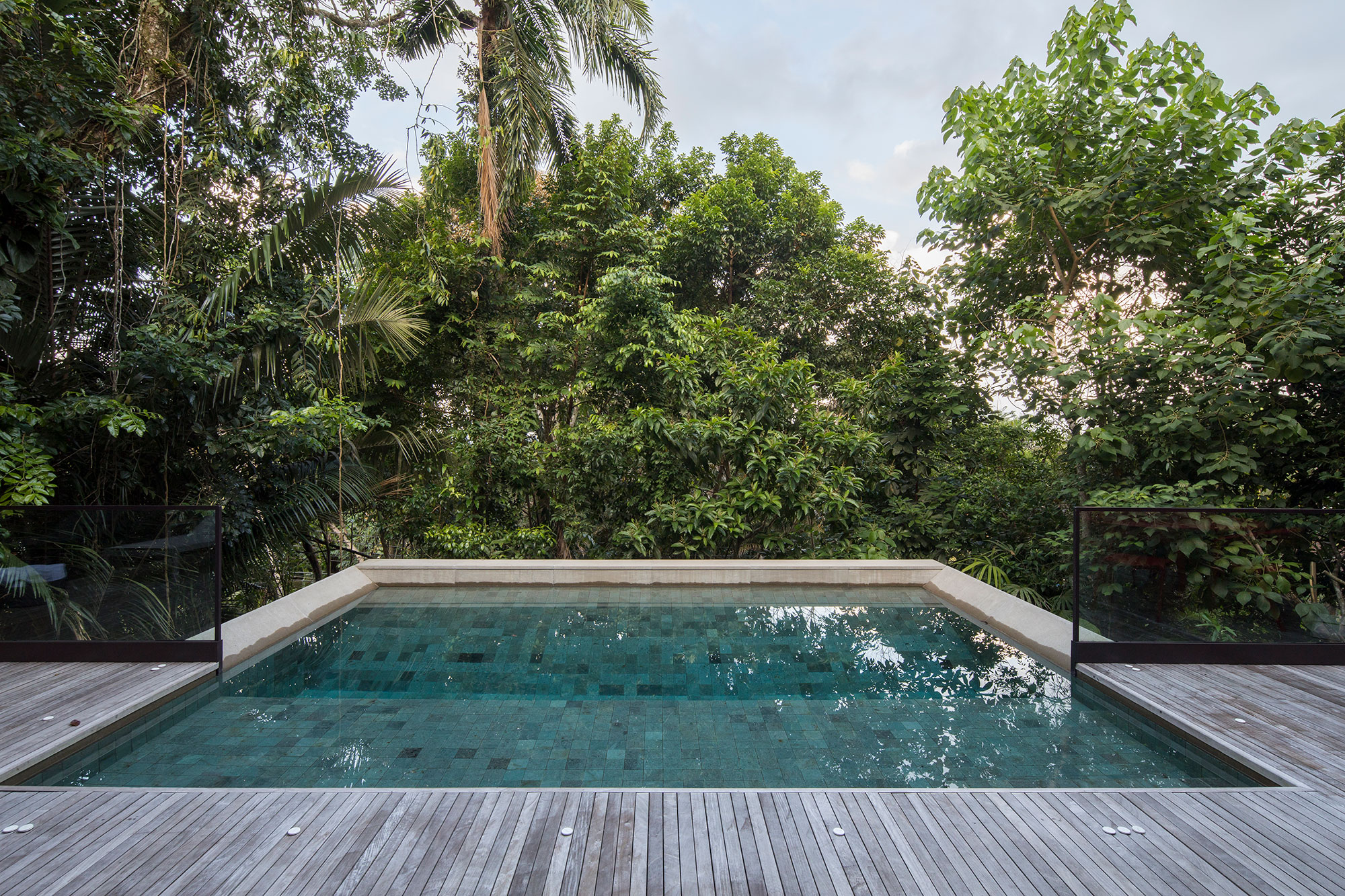 Casa de 153 m² se camufla em meio à natureza do litoral paulista. Projeto de Daniel Fromer, interiores de Julyana Bortolotto. Na foto, piscina com borda infinita e vista para o jardim.