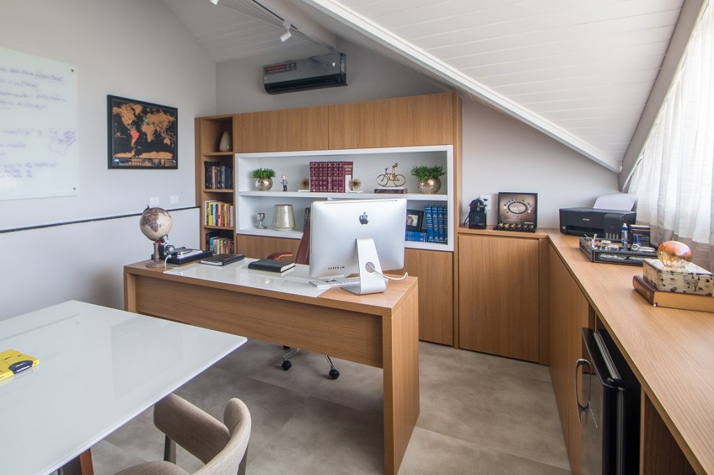 Casa de 500 m² possui detalhes dourados em todos os ambientes. Projeto de Ana Cano Milman. Na foto, escritório com mesa de reunião, marcenaria planejada e teto irregular.