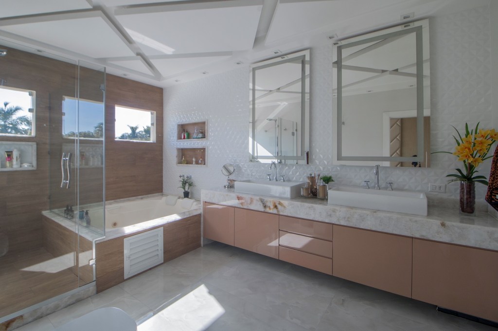 Casa de 500 m² possui detalhes dourados em todos os ambientes. Projeto de Ana Cano Milman. Na foto, banheiro com banheira. piso amadeirado e nichos.