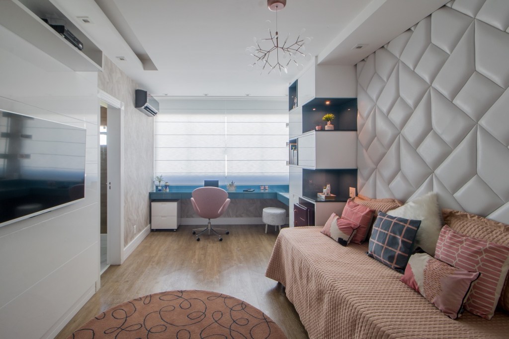 Casa de 500 m² possui detalhes dourados em todos os ambientes. Projeto de Ana Cano Milman. Na foto, quarto adolescente com bancada de estudo azul, tv e parede estofada.
