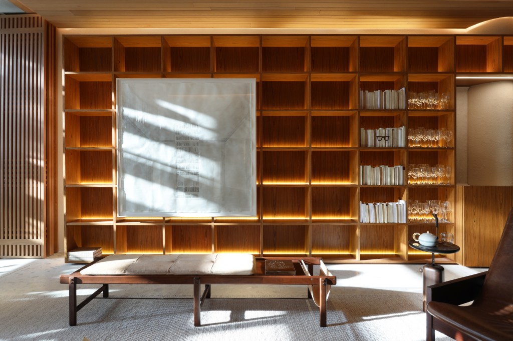 Casa de 82 m² tem projeto inspirado em Carlos Drummond de Andrade. Projeto de Bárbara Dundes. Na foto, estante iluminada com quadros e livros.