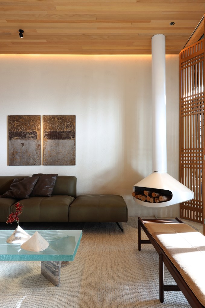 Casa de 82 m² tem projeto inspirado em Carlos Drummond de Andrade. Projeto de Bárbara Dundes. Na foto, sala com lareira, sofá e muxarabi.