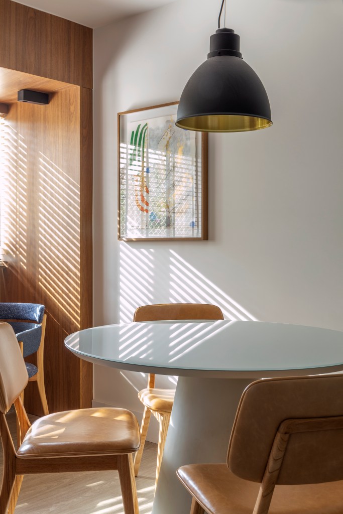 Sala de jantar pequena com mesa redonda branca e cadeiras de madeira.