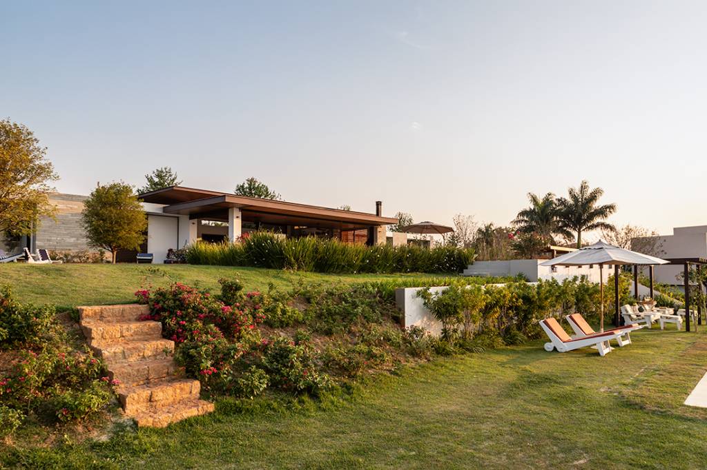 Casa de campo térrea tem vista para o laranjal e espaço para shuffleboard. Projeto de Gilda Meirelles. Na foto, fachada da casa com jardim.