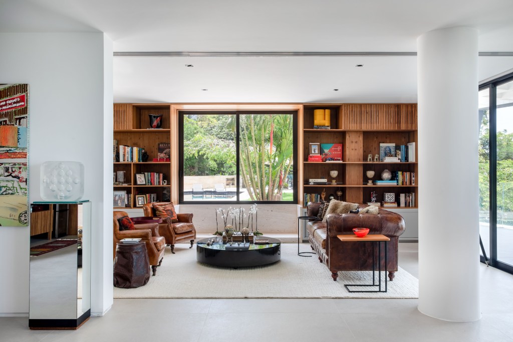 Sala de estar com tapete bege e estante em marcenaria com livros.