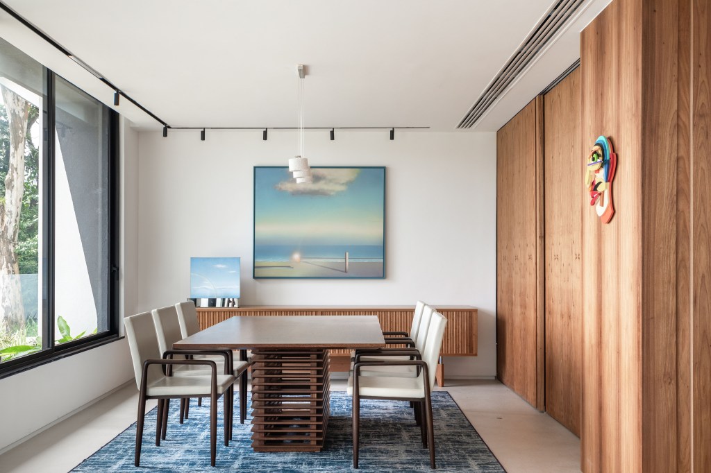casa-modernista-900m-cozinha-integrada-moveis-design-murad-sarria-arquitetura-renata-zappellini-09 Sala de jantar com mesa de madeira escura, tapete azul e buffet com madeira ripada.