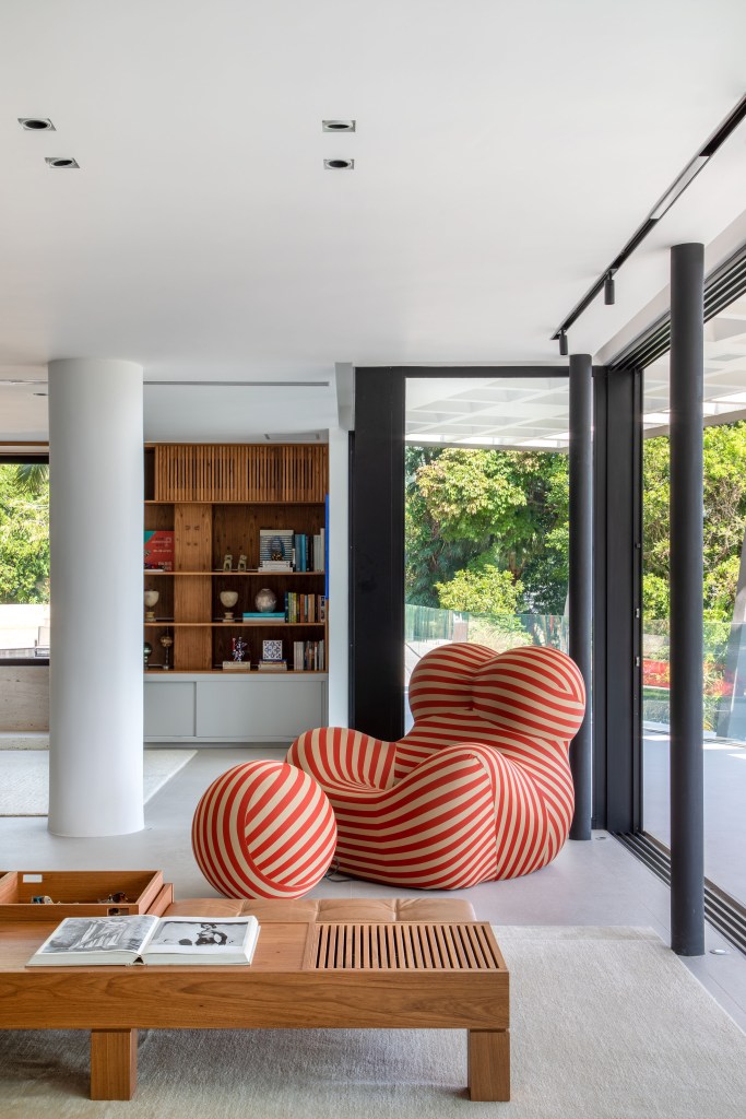 casa-modernista-900m-cozinha-integrada-moveis-design-murad-sarria-arquitetura-renata-zappellini-16 Sala de estar com janelas grandes e poltrona com pufe.