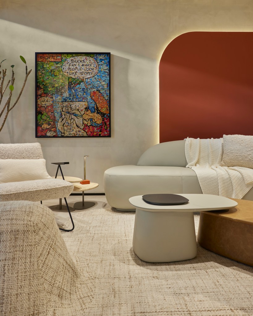 Sala de estar em tons beges com sofá curvo e obra de Vik Muniz