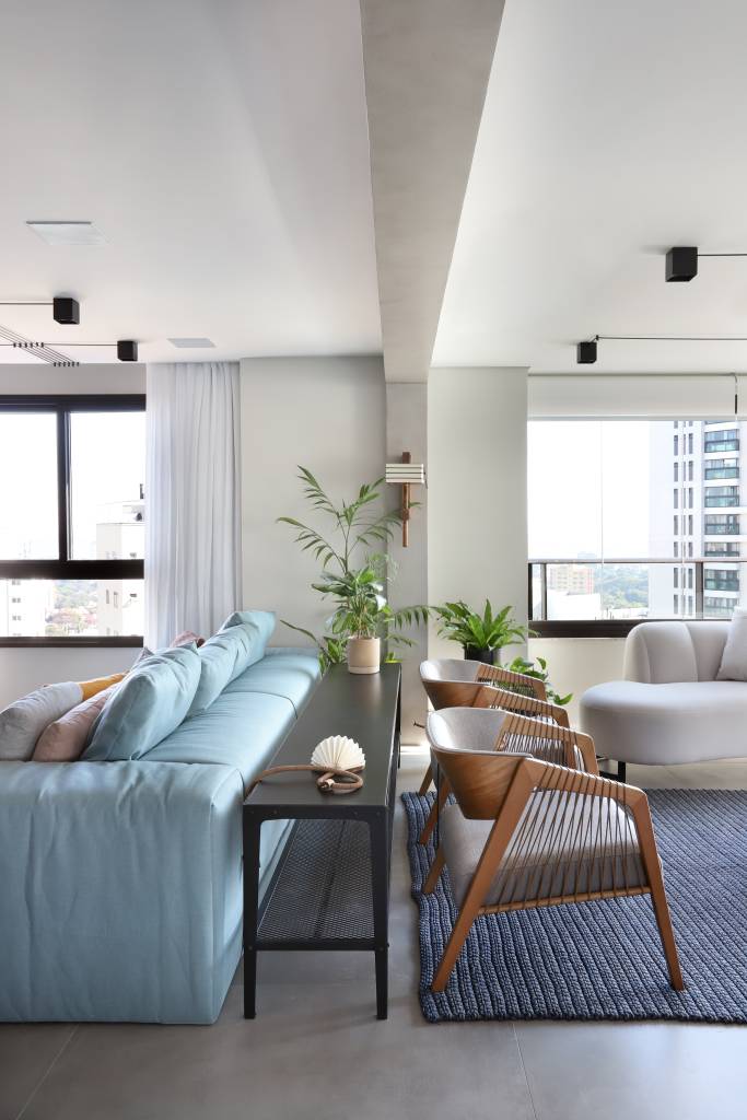 Sala de estar com sofá azul e aparador preto atrás do sofá.