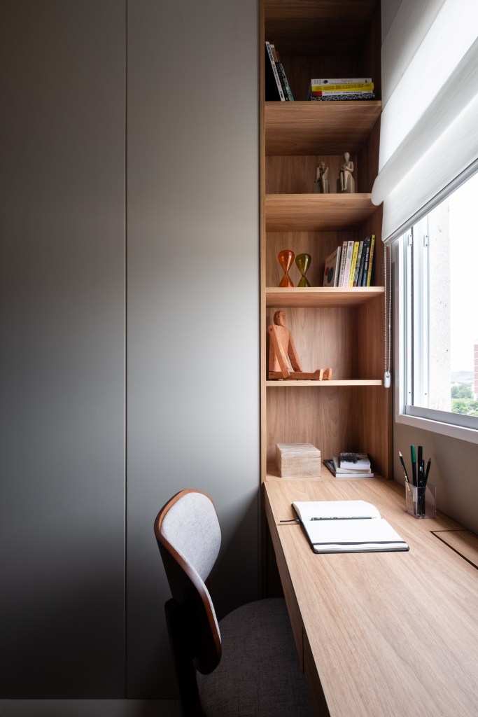 Home office pequeno com bancada de madeira e armário cinza.