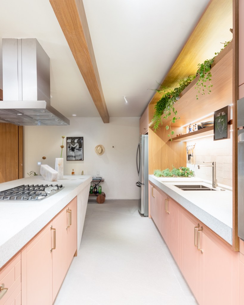 Cozinha une marcenaria rosa, brises, horta e granito branco. Projeto de Bruno Moraes para a CASACOR SP 2023. NA foto, cozinha com marcenaria rosa, bancada de granito e horta.