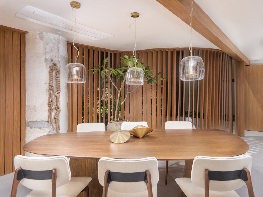 Cozinha une marcenaria rosa, brises, horta e granito branco. Projeto de Bruno Moraes para a CASACOR SP 2023. Na foto, sala de jantar com brise de madeira e mesa de madeira.