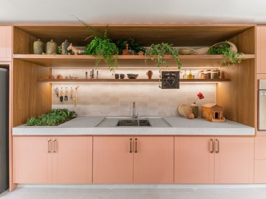 Cozinha une marcenaria rosa, brises, horta e granito branco. Projeto de Bruno Moraes para a CASACOR SP 2023. Na foto, cozinha com horta na bancada da pia. Marcenaria rosa.