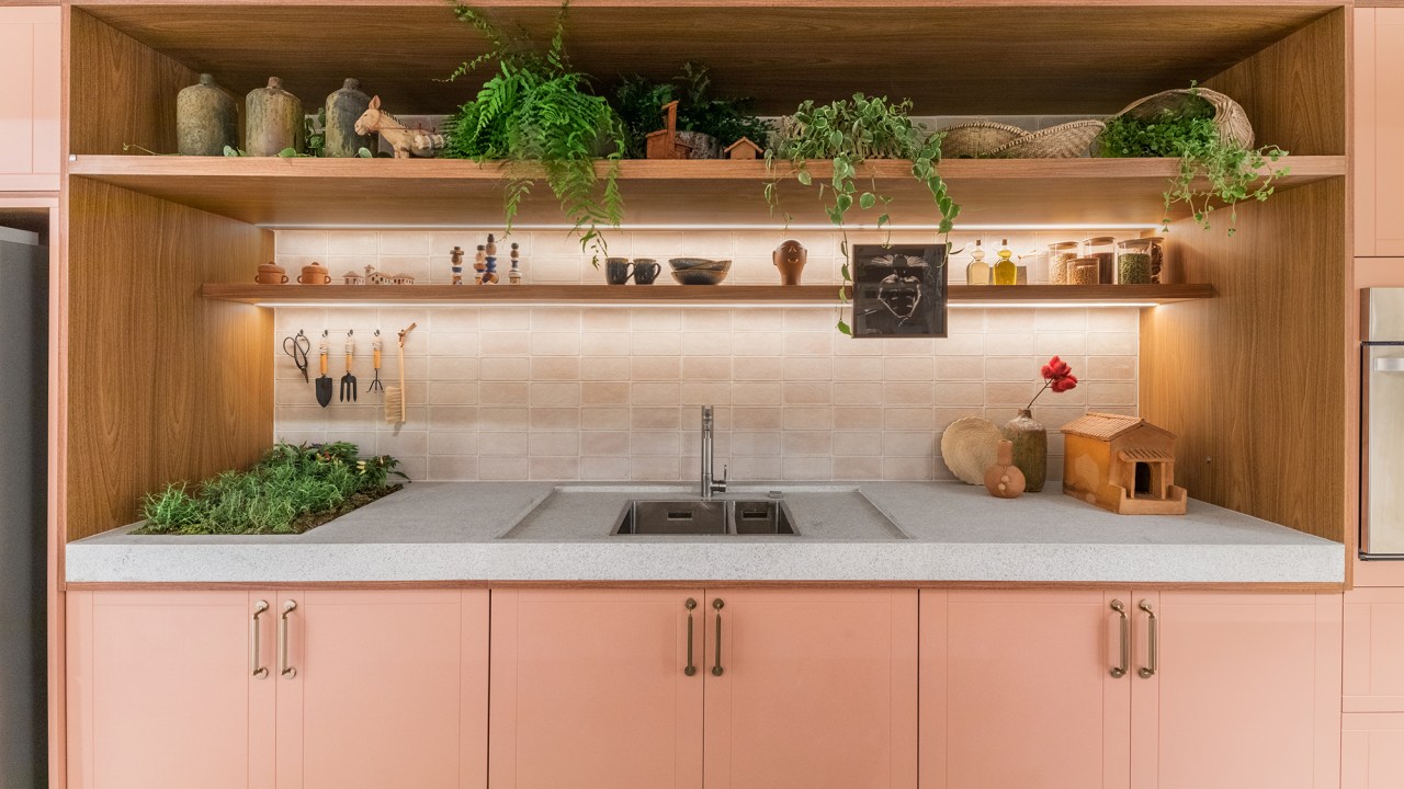 Cozinha une marcenaria rosa, brises, horta e granito branco. Projeto de Bruno Moraes para a CASACOR SP 2023. Na foto, cozinha com horta na bancada da pia. Marcenaria rosa.