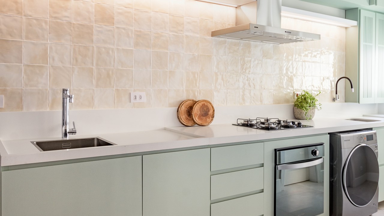 Cozinha verde mint e mesa de trabalho em destaque marcam este apê de 90 m². Projeto Suellen Figueiredo. Na foto, cozinha com armário menta e lavanderia.