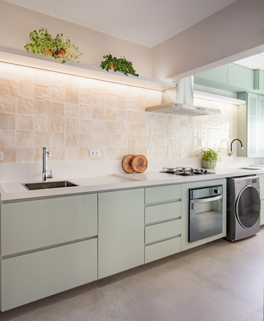 Cozinha verde mint e mesa de trabalho em destaque marcam este apê de 90 m². Projeto Suellen Figueiredo. Na foto, cozinha com armário menta e lavanderia.