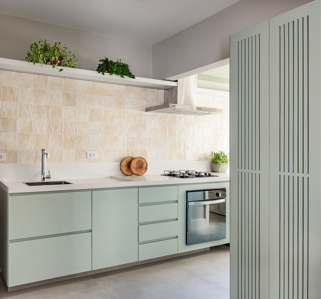 Cozinha verde mint e mesa de trabalho em destaque marcam este apê de 90 m². Projeto Suellen Figueiredo. Na foto, cozinha com armário menta e ripado.