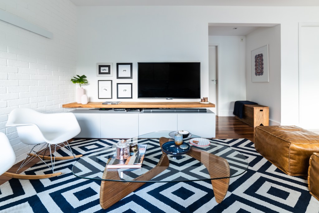 Sala de estar pequena com tapete geométrico azul e branco.