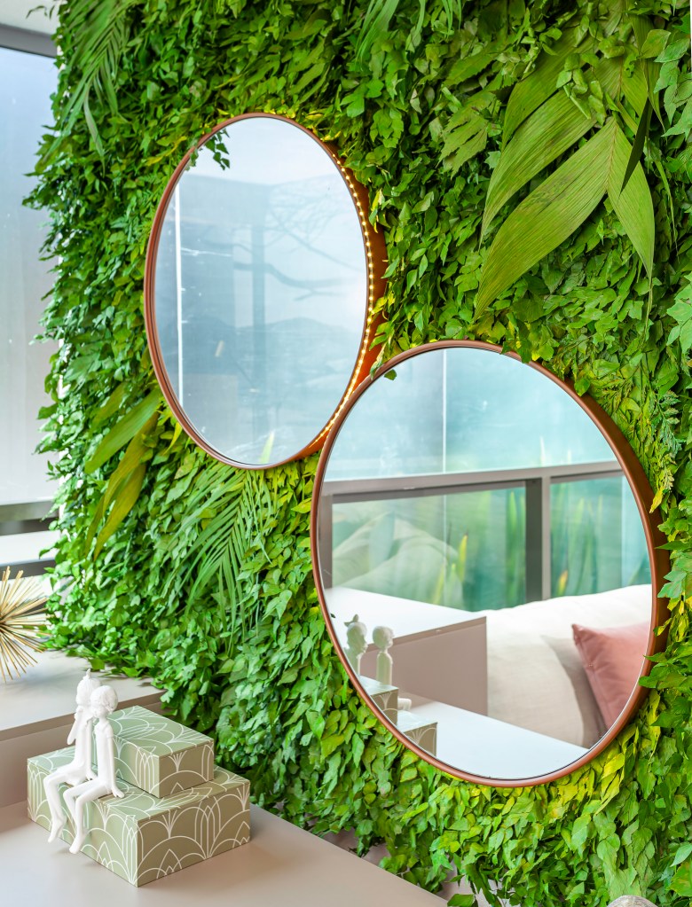 Jardim vertical com plantas preservadas, penteadeira e espelhos redondos.