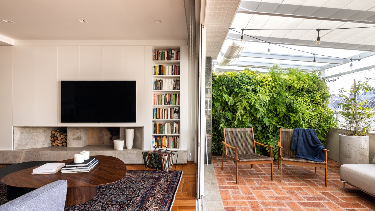 Sala de estar e tv com painel de marcenaria branco e varanda integrada.