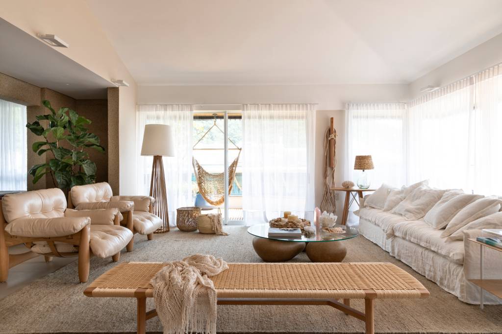 materiais-naturais-clima-praia-ape-alessandra-ambrosio-juliana-pippi-04-sala Sala de estar com decoração clean, cortina branca, sofá branco e duas poltronas Moles.