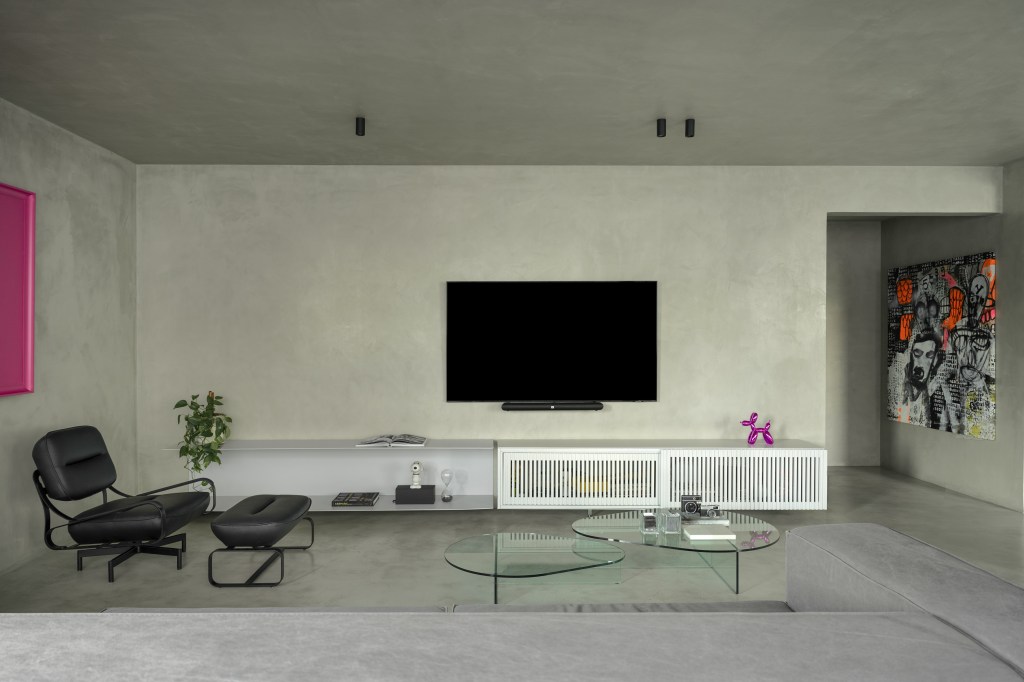 Minimalista: apê de 300 m² utiliza poucas cores e efeitos de luz no décor. Projeto de Lucas Lage. Na foto, sala de tv com rack, poltrona e quadros.
