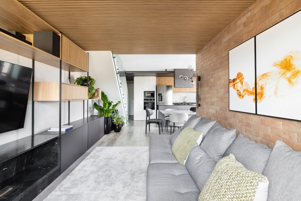 Sala de estar integrada com cozinha e jantar com sofá cinza e tapete cinza.