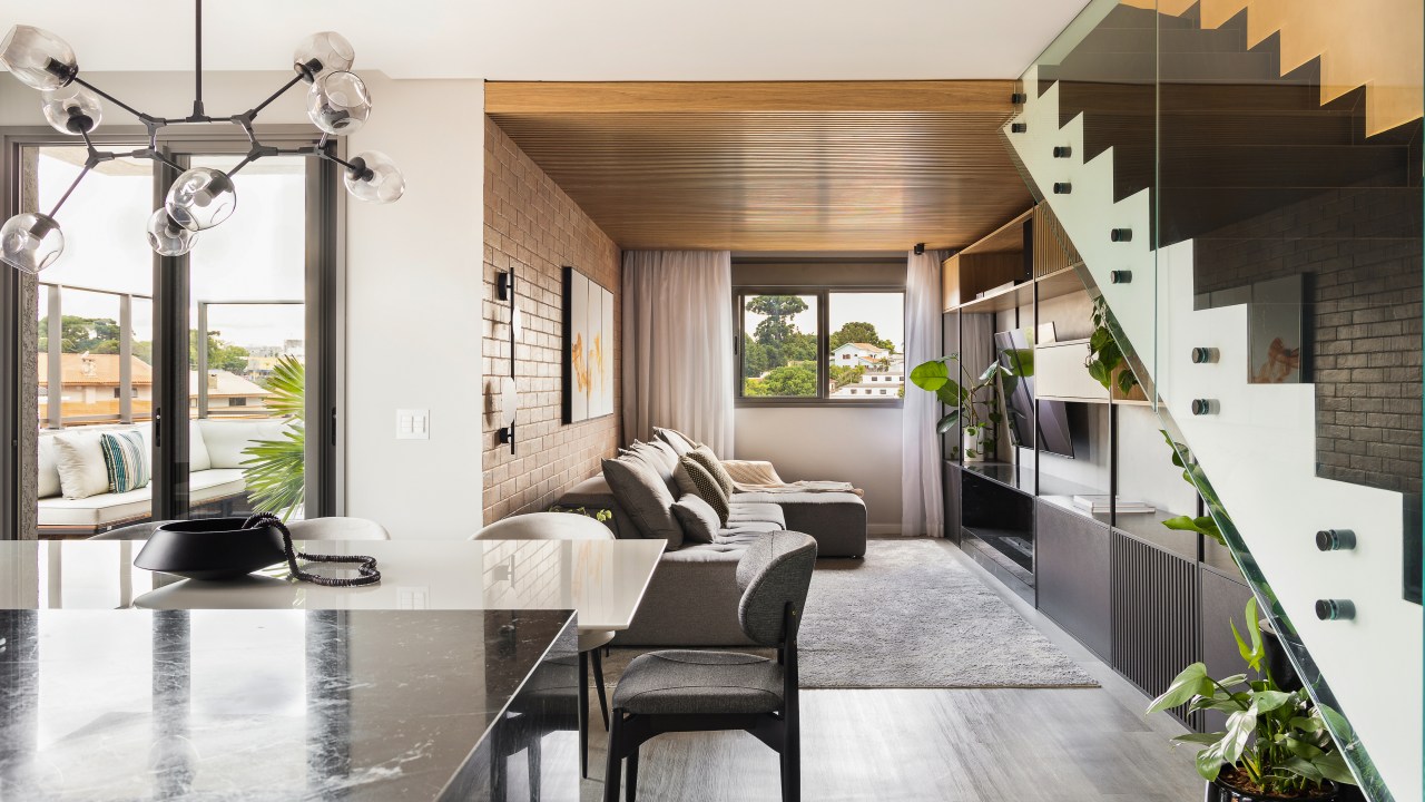 Sala de estar integrada com cozinha, tapete e bancada preta.