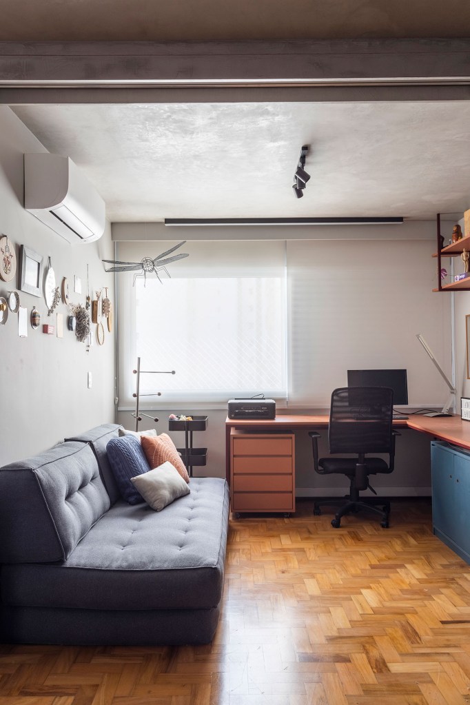 Piso de taquinho norteia décor de apê de 120 m². Projeto de Grafito Studio Criativo. Na foto, escritório com sofá cinza e bancada de trabalho.