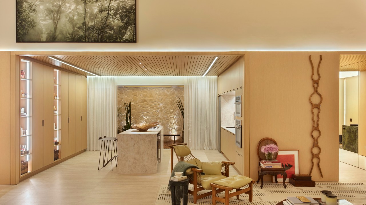 Quiet luxury e feng shui indiano marcam este loft de 120 m², Projeto de Bianca Da Hora Arquitetura para a CASACOR SP 2023. Na foto, cozinha com ilha, poltrona, teto ripado, quadros e tapete.
