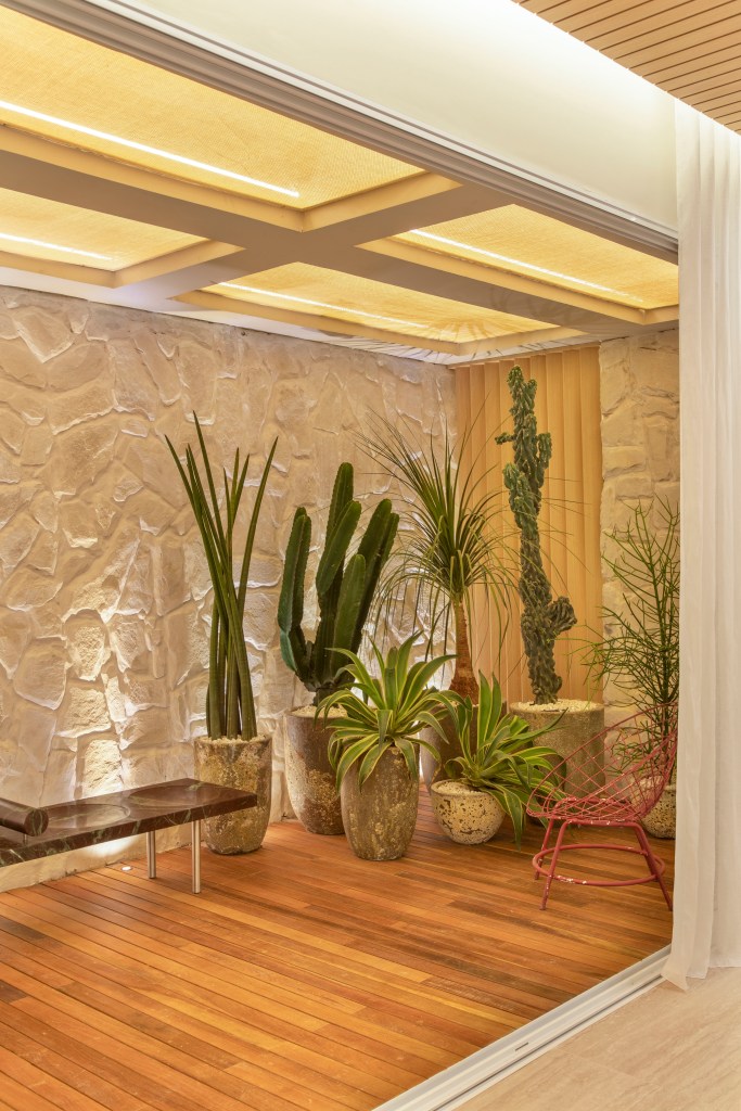 Quiet luxury e feng shui indiano marcam este loft de 120 m², Projeto de Bianca Da Hora Arquitetura para a CASACOR SP 2023. Na foto, jardim com parede de pedra, vasos e banco.